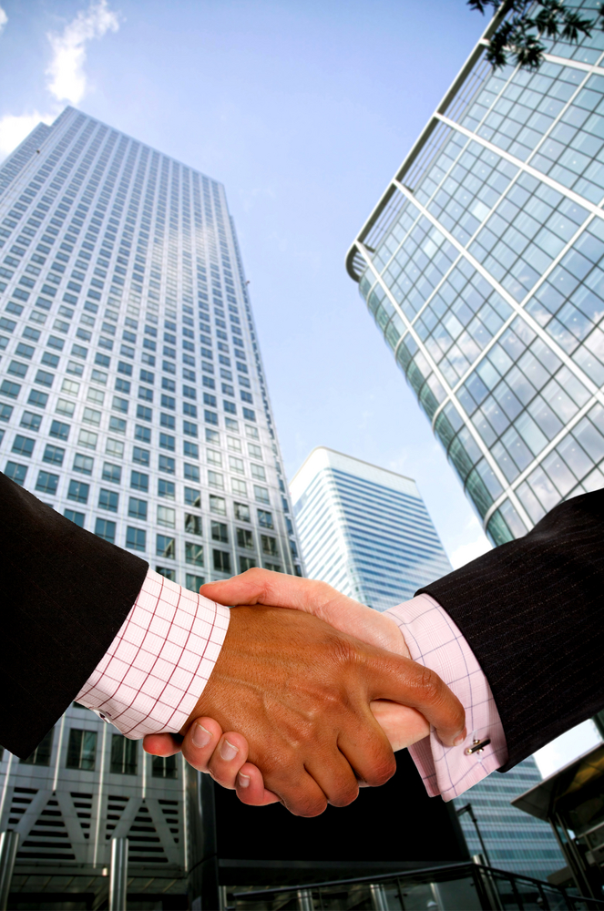 diverse business men shaking hands in a corporate environment - vertical